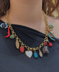 Necklace with colorful charms worn by a person against a dark background