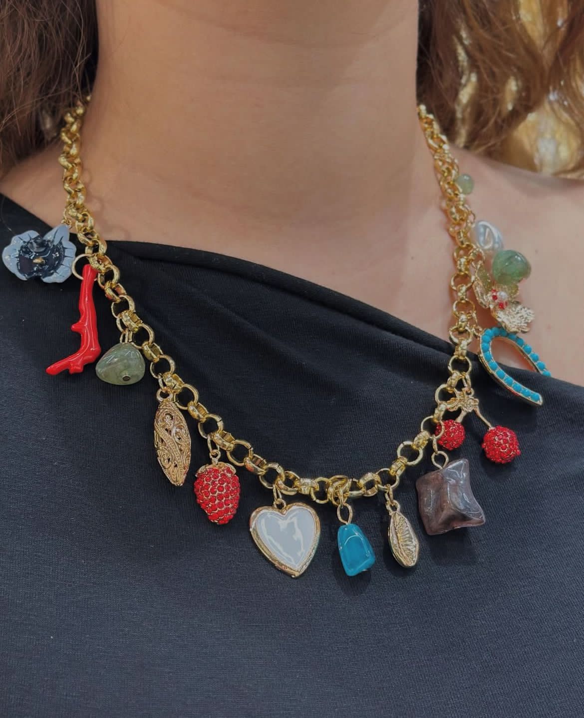 Necklace with colorful charms worn by a person against a dark background